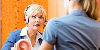 Femme portant un casque qui parle avec une audioprothésiste