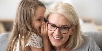 Petite fille chuchotant à l'oreille d'une femme âgée