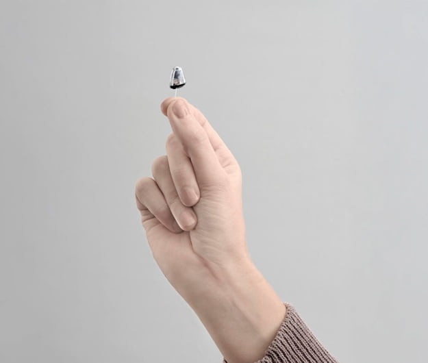 Appareil auditif invisible Audika Blink mini tenu entre les doigts