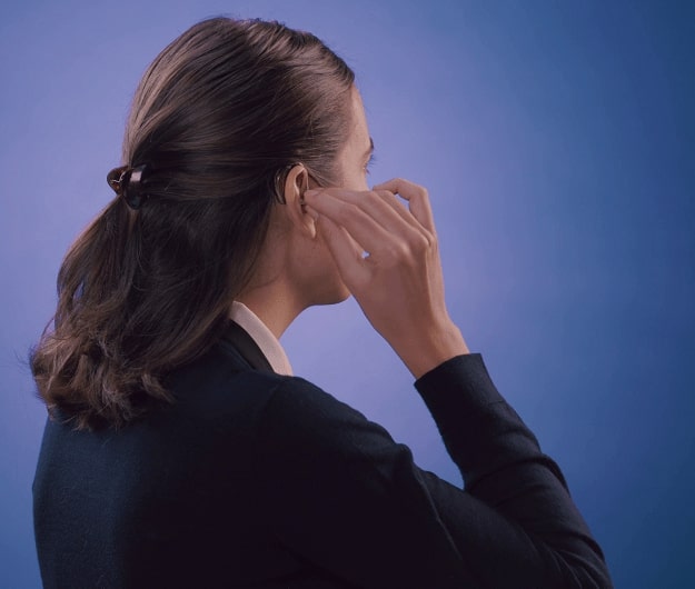 Une femme en train de mettre un appareil auditif contours d'oreilles