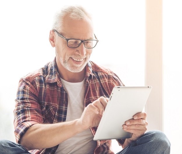Un homme s'amuse de ce qu'il voit sur sa tablette