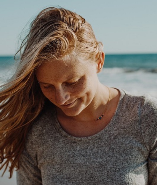 Une femme sur la plage les cheveux au vent