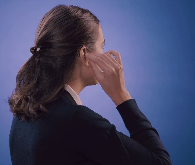 Une femme en train de mettre un appareil auditif contours d'oreilles