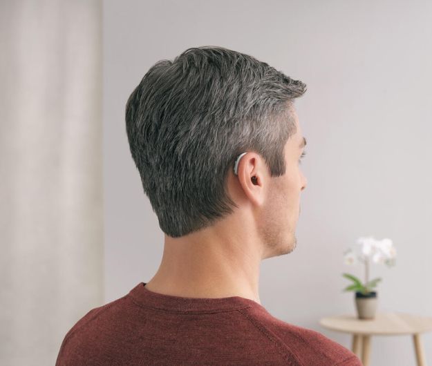 Homme portant un appareil auditif dans un environnement intérieur lumineux