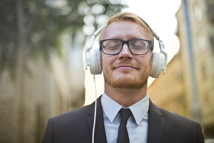 Un homme en costume écoute des exercices auditifs avec un casque pour améliorer sa perception sonore et gérer les acouphènes.