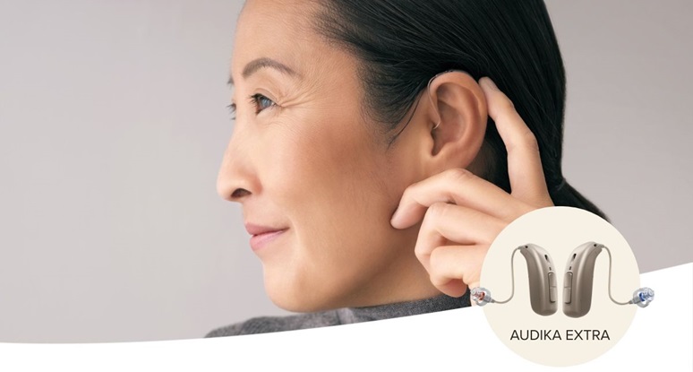Femme ajustant ses aides auditives Audika Extra