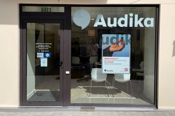 Façade du centre auditif Audika à Thônes, avec vitrine lumineuse et affiche promotionnelle.