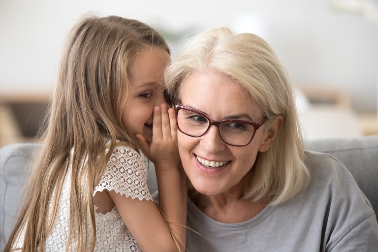 Grand-mère avec petite fille qui chuchote dans son oreille