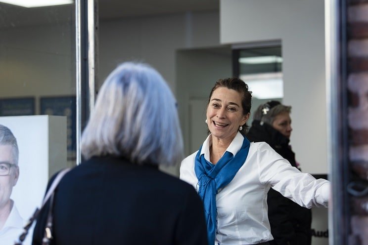 Les experts Audika accueillent une cliente dans un centre de soins auditifs.