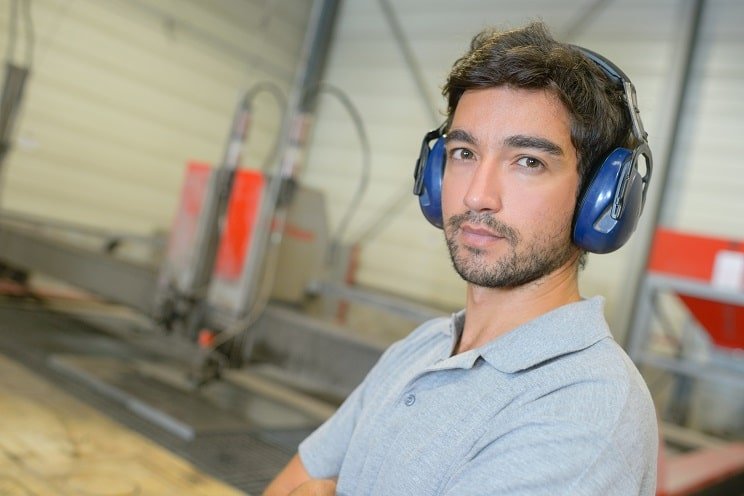 Jeune homme portant un casque antibruit dans un environnement industriel.