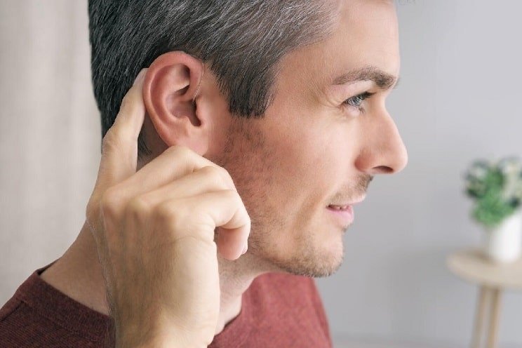 Homme ajustant ses appareils auditifs