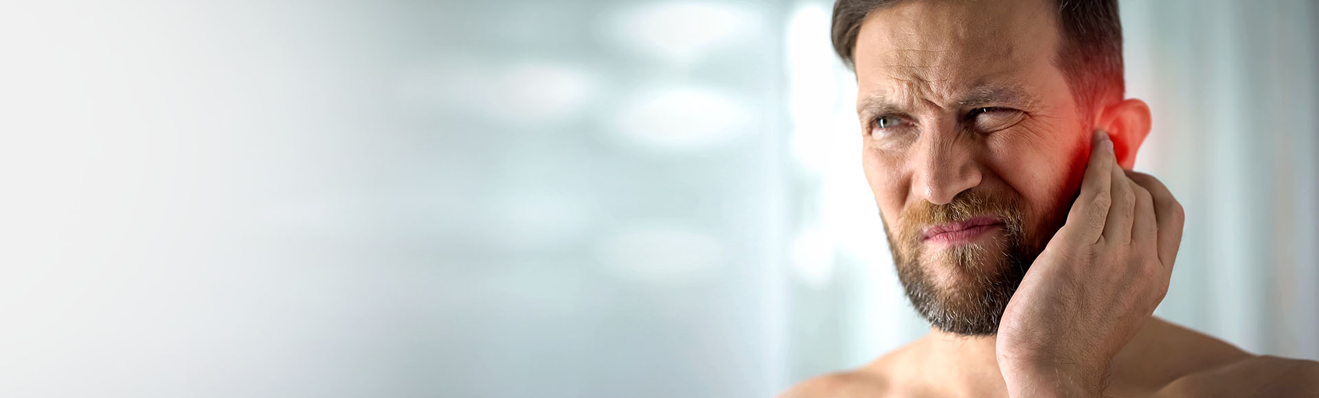 Personne touchant son oreille en raison d'acouphènes ou de sifflements persistants.