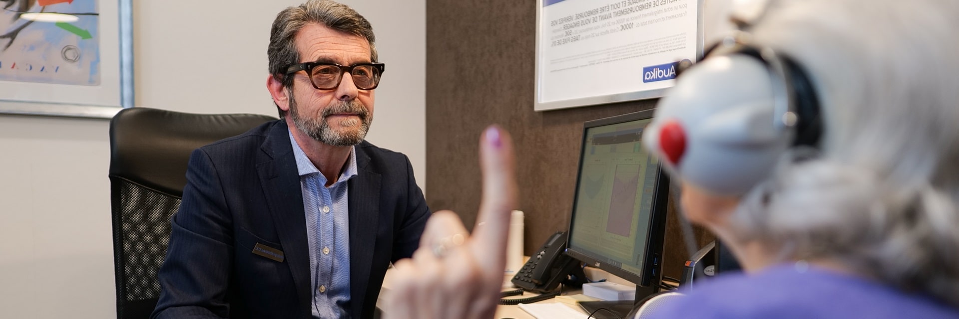 Femme âgée portant un casque audio lors d'un test auditif avec un audioprothésiste.