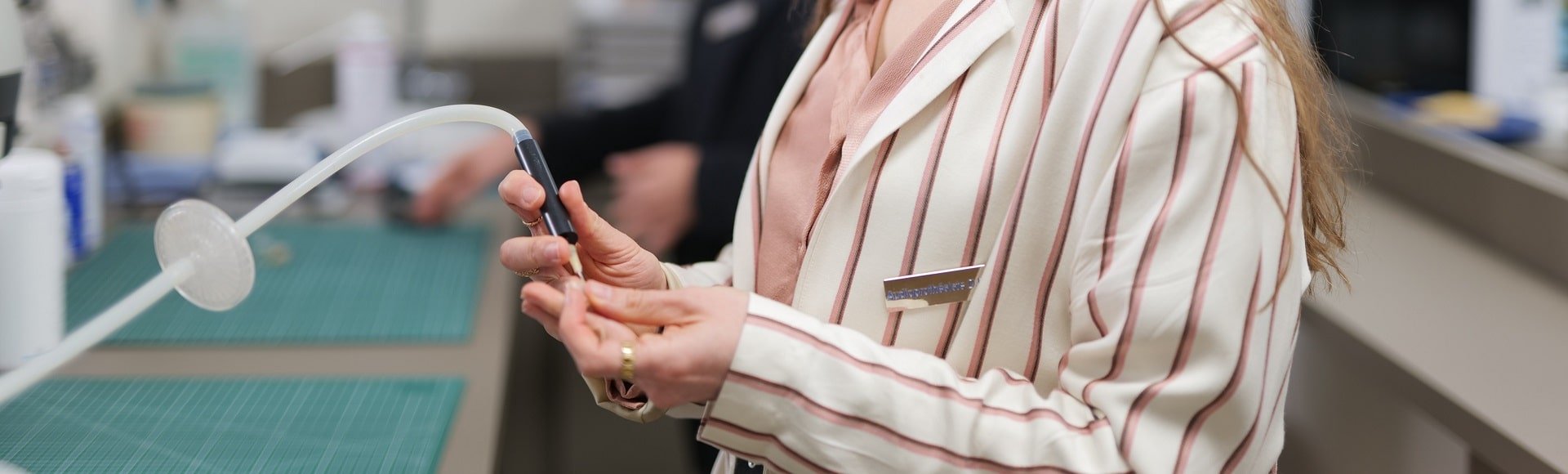 Réparation d’un appareil auditif par une audioprothésiste dans un laboratoire.