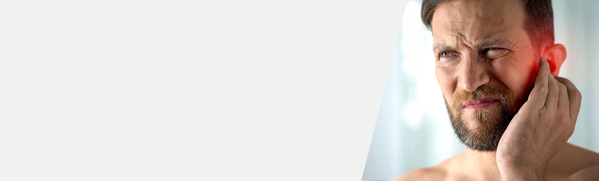 Un homme souffrant d’acouphènes touche son oreille rouge.
