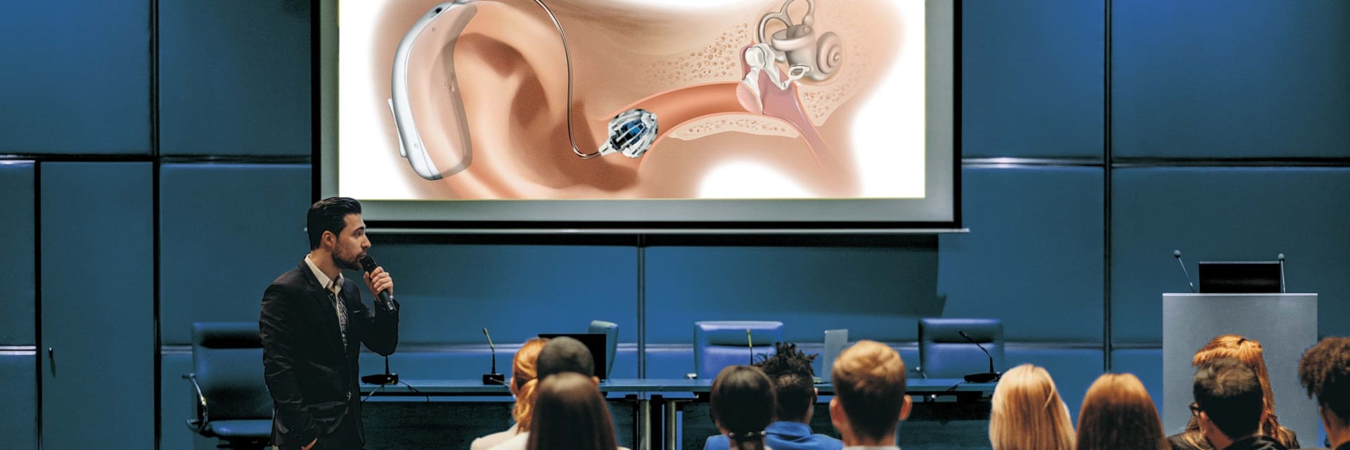 Audioprothésiste exposant un schéma d’appareil auditif lors d’une conférence sur les pôles d’expertise