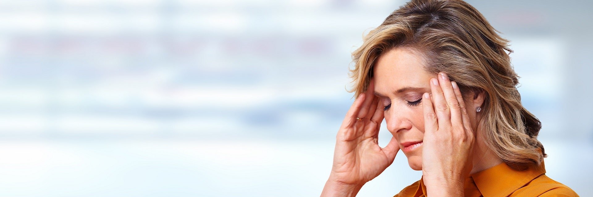 Femme souffrant de maux de tête ou de stress, tenant ses tempes avec ses mains.