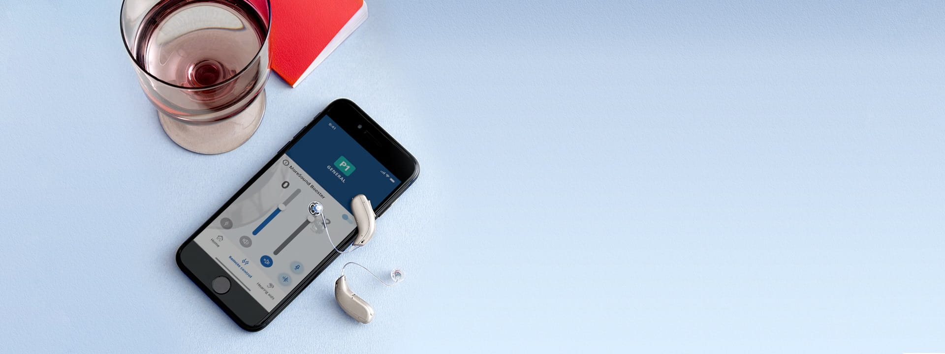 Des aides auditives posées à côté d’un smartphone avec une application de réglage ouverte.