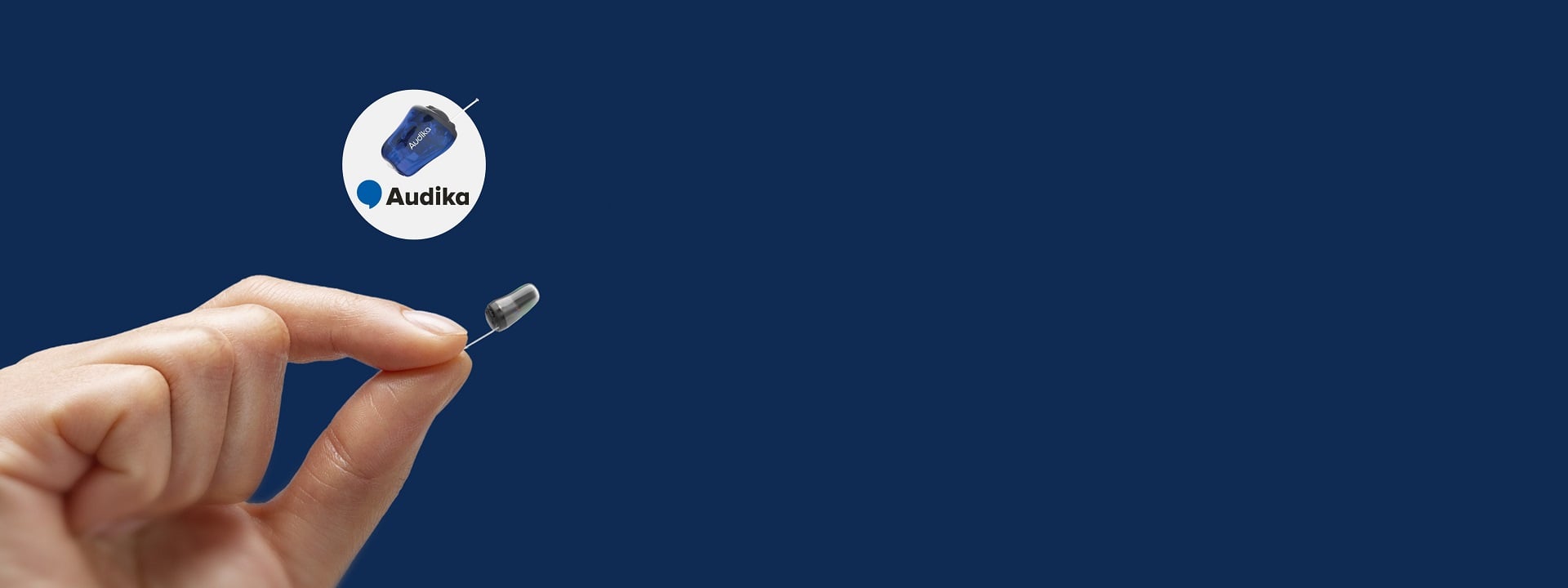 Main tenant un très petit appareil auditif Audika avec un embout intra-auriculaire, présenté sur un arrière-plan bleu.