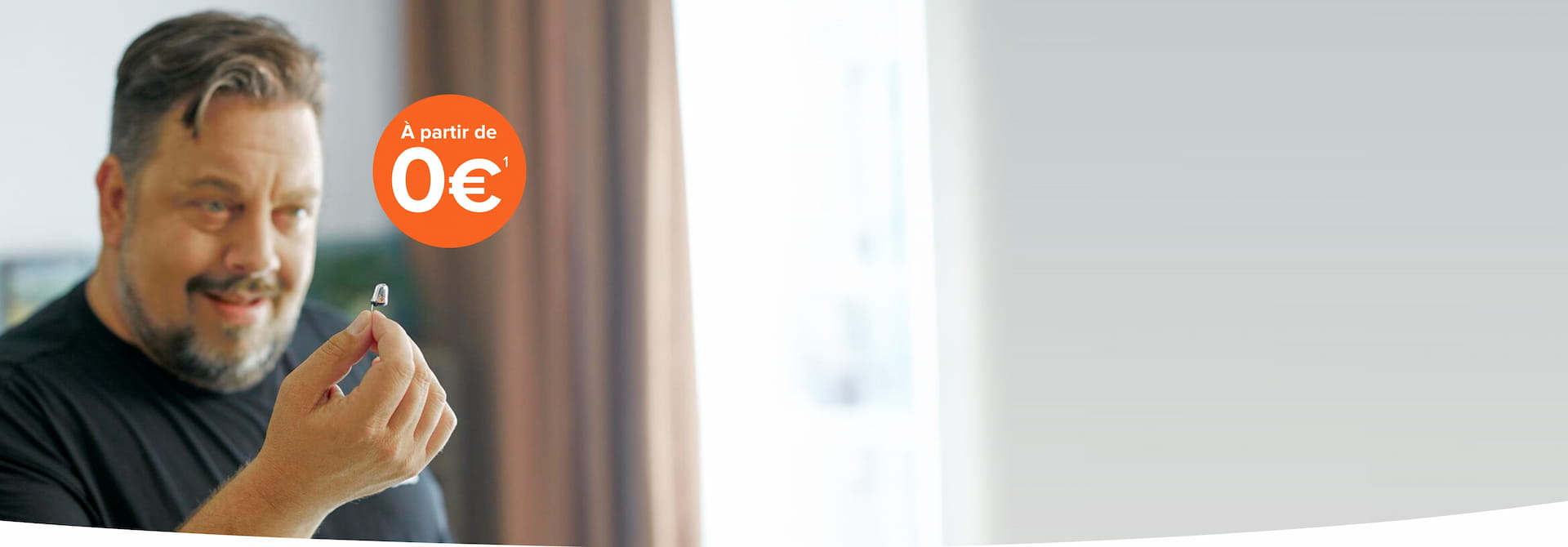 Un homme tenant un appareil auditif avec une offre affichée à partir de 0€.