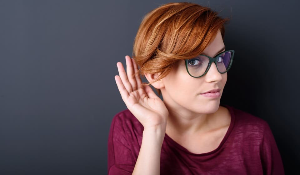 jeune femme tendant l'oreille pour entendre mieux