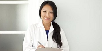 audioprothésiste professionnelle en blouse blanche prenant des notes sur un clipboard