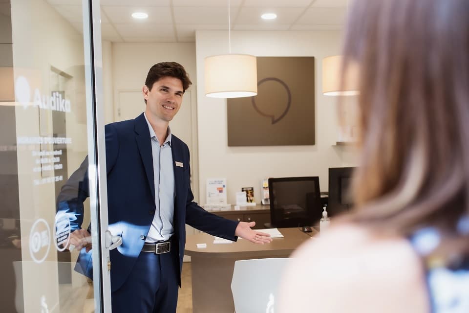 Un audioprothésiste accueille une patiente dans un centre auditif