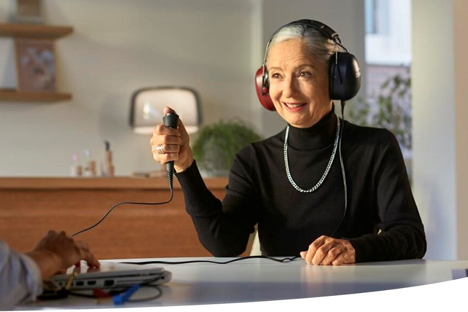 Femme portant un casque auditif et tenant un bouton pendant un test auditif.