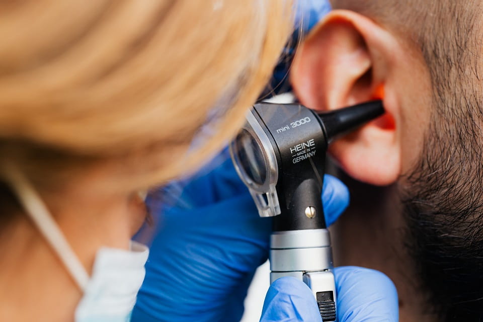 Examen auditif avec otoscope effectué par un professionnel sur un patient