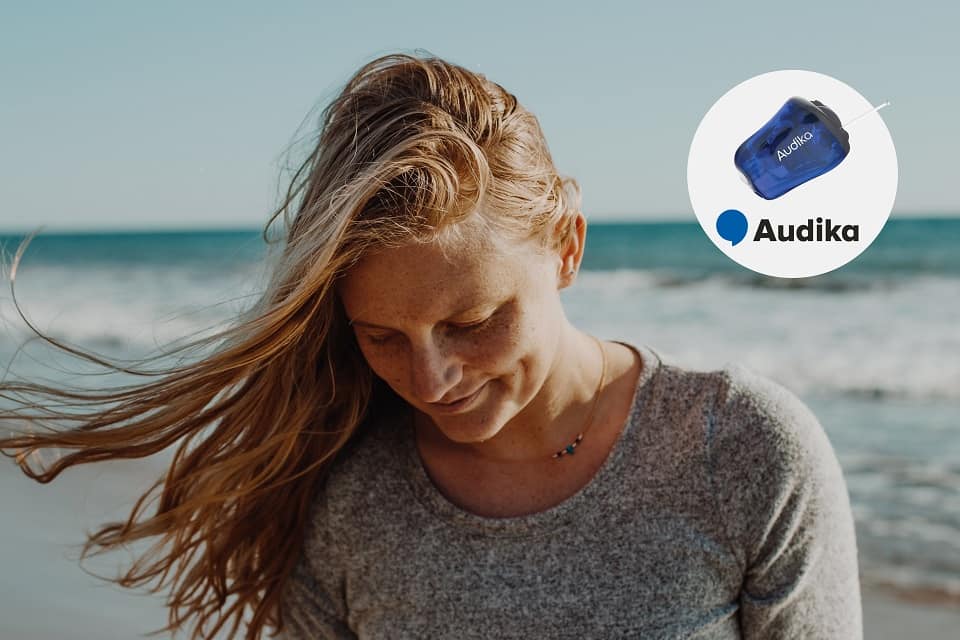 Femme utilisant une prothèse auditive Audika près de la plage