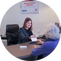 Assistante remettant un document à une patiente dans un centre auditif.