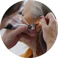 Examen auditif avec otoscope sur une patiente adulte.