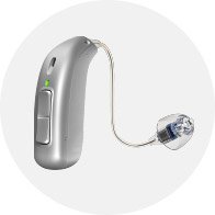 Appareil auditif argenté moderne avec embout auriculaire transparent et câble fin.