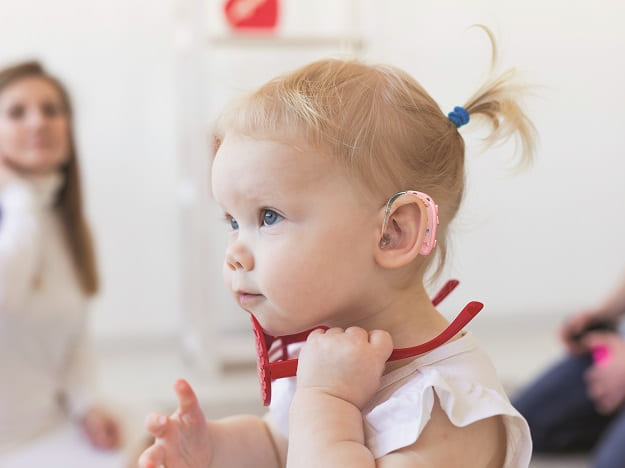 Un bébé qui porte un appareil auditif