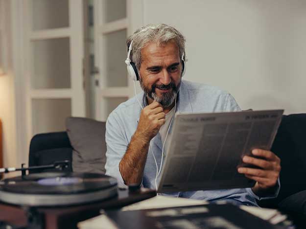 Une homme écoute de la musique en lisant son journal