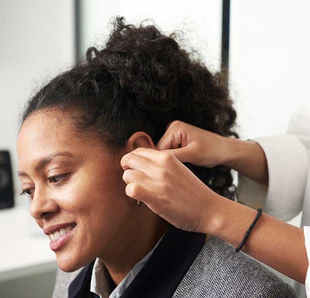 Une femme se fait poser un appareil auditif