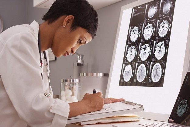 Audioprothésiste analysant des scans cérébraux et prenant des notes