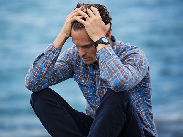 Un homme en détresse près de l’eau, potentiellement lié au stress et à la surdité brusque