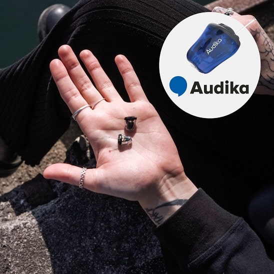 Appareils auditifs invisibles Audika posés sur une paume de main