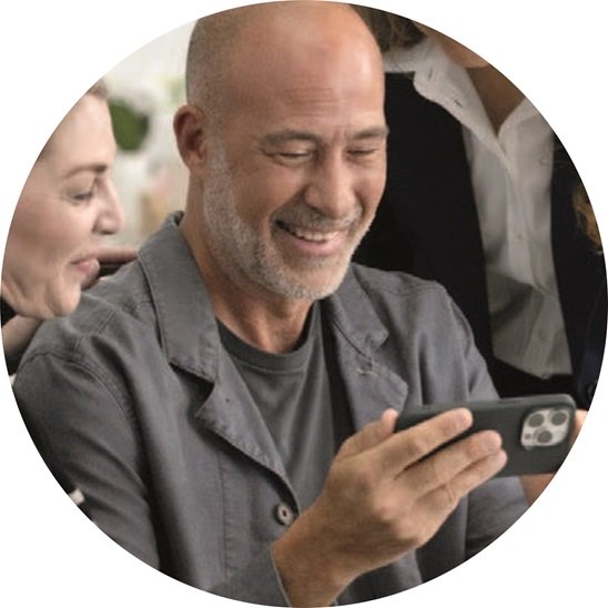 Homme regarde vidéo sur son téléphone avec des appareils auditifs connectés en Bluetooth