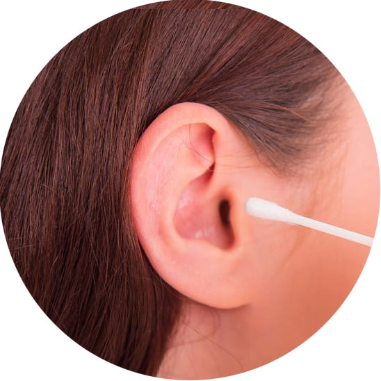Un coton-tige nettoie délicatement l'entrée d'une oreille, entourée de cheveux bruns. La scène met en avant l'hygiène auditive, importante pour préserver une bonne santé auditive.