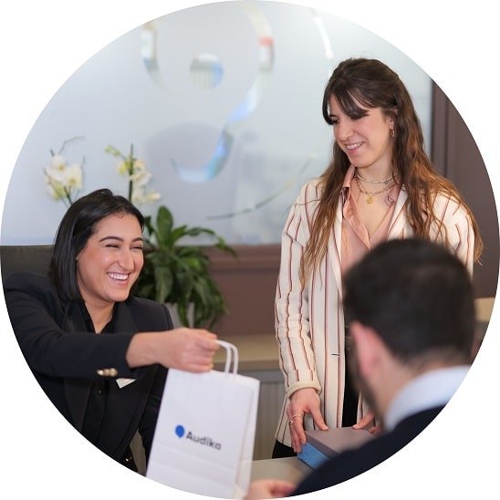 L'équipe d'un centre auditif remet un sac Audika au patient