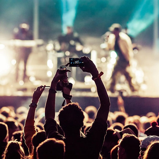 Foule applaudissant un groupe de musique sur scène pendant un concert en plein air.