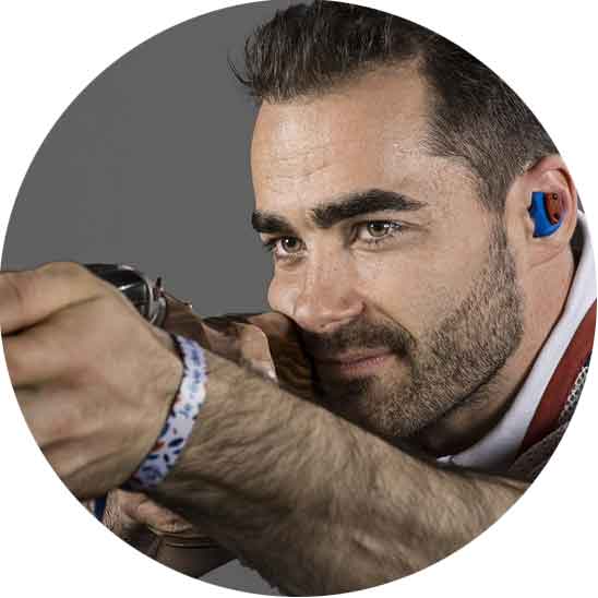 Homme en train de tirer à la carabine avec des bouchons de protection dans les oreilles