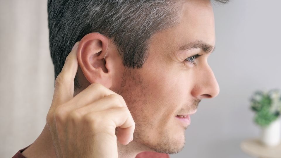 Uomo che si tocca l’orecchio con la mano.