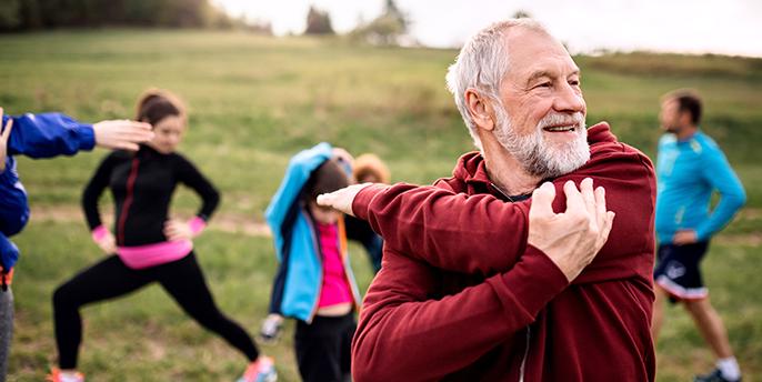 Gruppo di persone che fanno esercizi di stretching all’aperto per favorire l’equilibrio e il benessere.