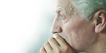 Un orecchio umano in primo piano con capelli grigi visibili, contestualizzato in un ambiente luminoso sfocato.