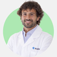 Diego Florio, audioprotesista con camice bianco su sfondo verde.