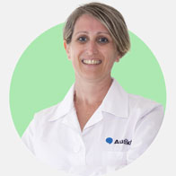 Specialista in cura dell'udito Elisa Chiostri con camice bianco e sfondo verde.