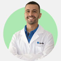 Renato Regalbuto, audioprotesista con camice bianco e logo Audibel